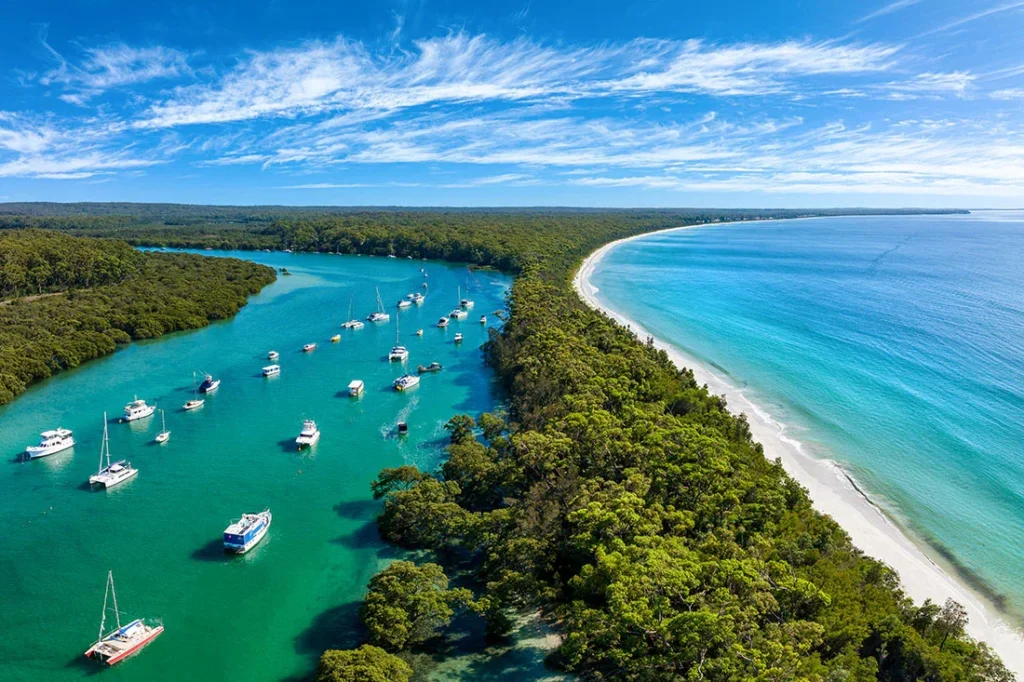Aerial view of a Shoalhaven inlet with boats and white sand beach